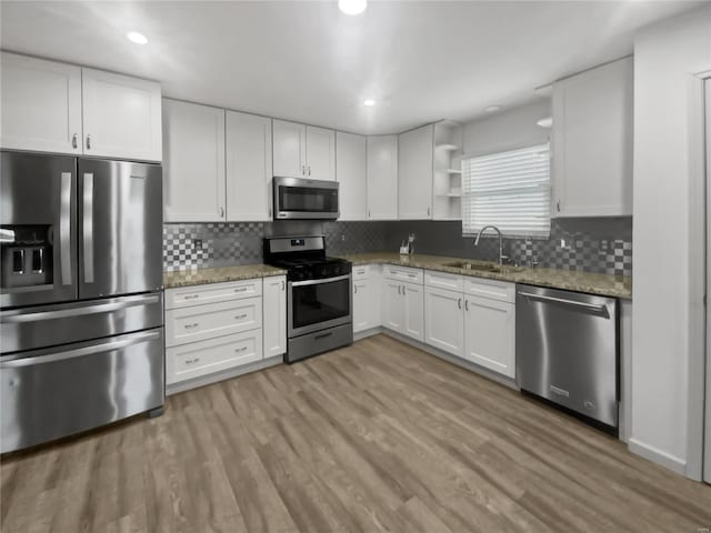 kitchen with stainless steel appliances, open shelves, a sink, and white cabinets