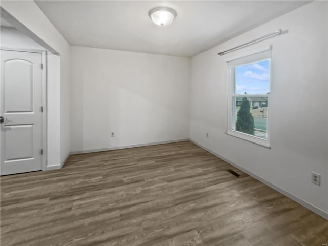 unfurnished room with visible vents, baseboards, and wood finished floors