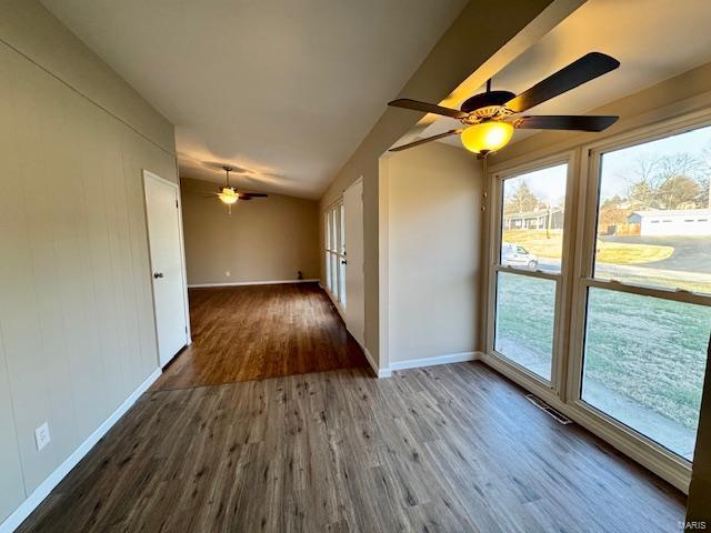 spare room featuring vaulted ceiling, baseboards, a ceiling fan, and wood finished floors