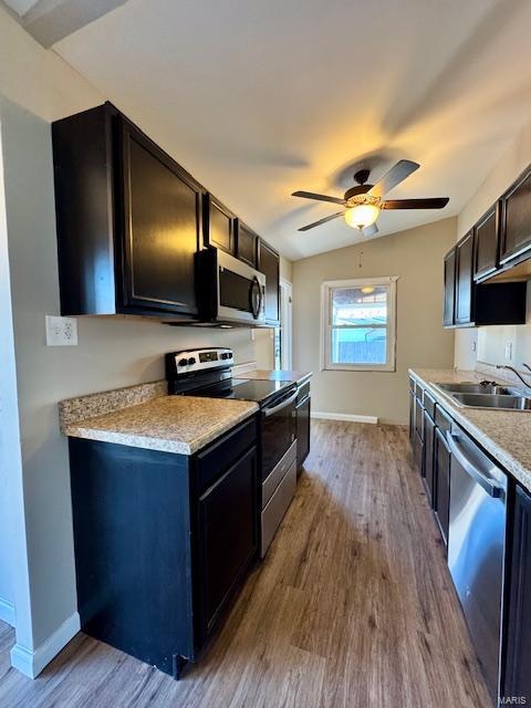 kitchen featuring light countertops, wood finished floors, stainless steel appliances, a ceiling fan, and a sink