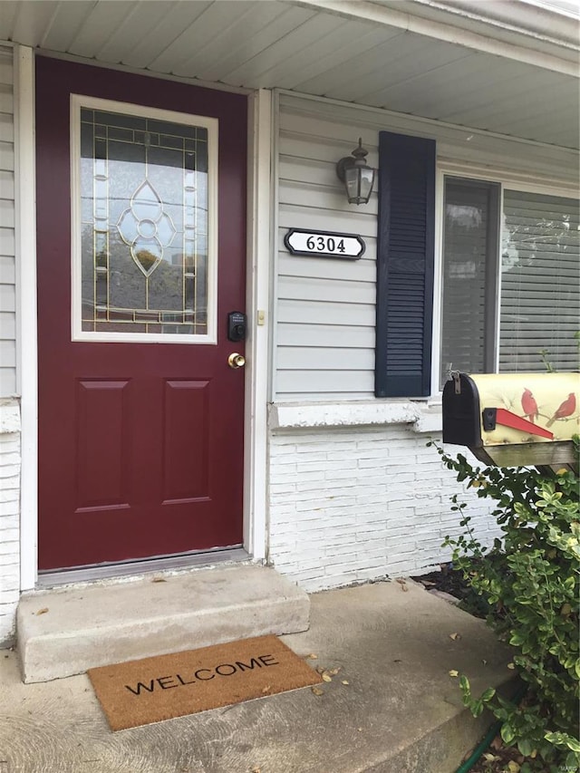 doorway to property with covered porch and brick siding