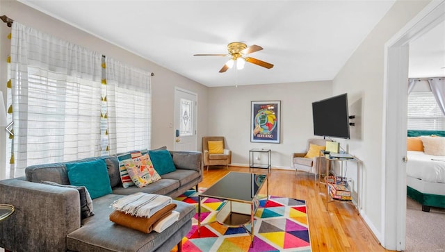 living room featuring baseboards, a ceiling fan, and wood finished floors