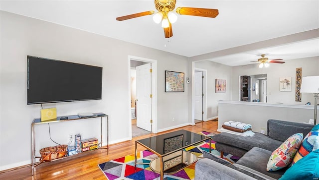 living room with wood finished floors, a ceiling fan, and baseboards