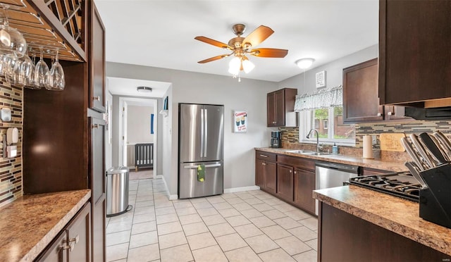 kitchen featuring stainless steel appliances, dark brown cabinets, backsplash, and a sink