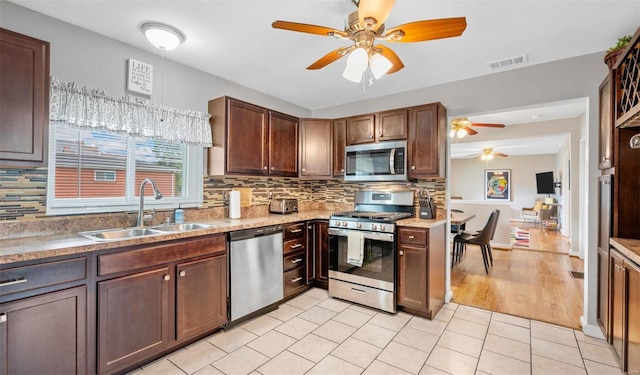 kitchen featuring decorative backsplash, visible vents, stainless steel appliances, and a sink