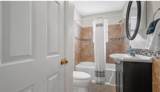 bathroom with toilet, vanity, tile walls, decorative backsplash, and shower / bath combination with curtain