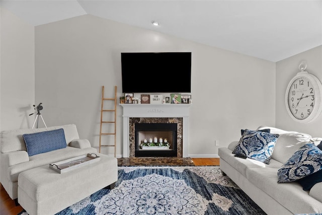 living room featuring vaulted ceiling, wood finished floors, a high end fireplace, and baseboards