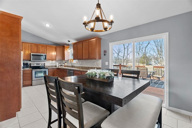 dining space featuring vaulted ceiling, light tile patterned floors, baseboards, and an inviting chandelier