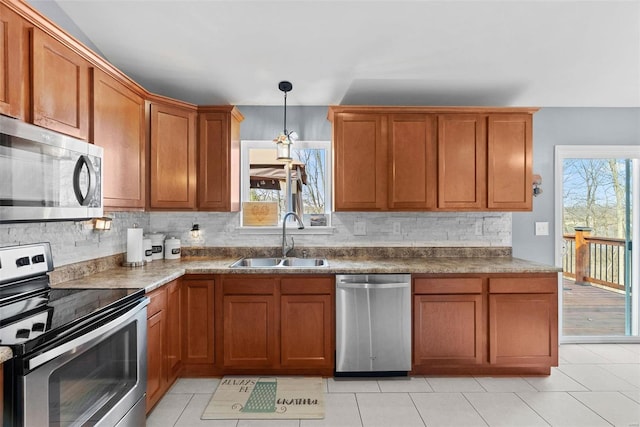 kitchen featuring hanging light fixtures, backsplash, appliances with stainless steel finishes, brown cabinetry, and a sink