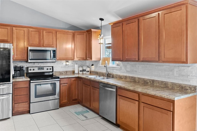 kitchen featuring brown cabinetry, lofted ceiling, appliances with stainless steel finishes, a sink, and backsplash