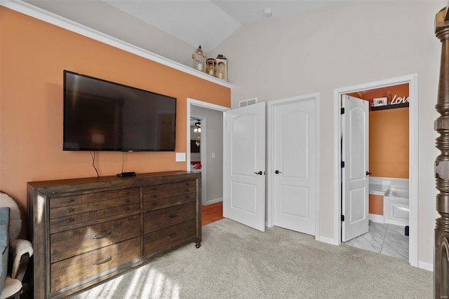 bedroom featuring ensuite bath, vaulted ceiling, a closet, and light colored carpet