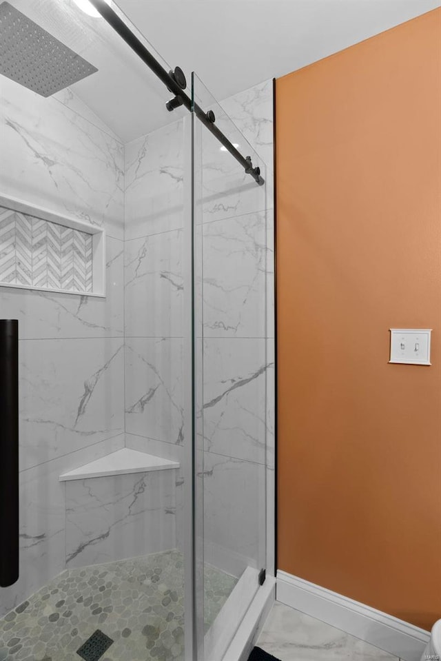 bathroom with marble finish floor, a marble finish shower, and baseboards