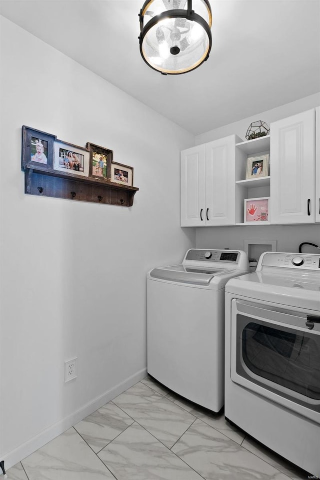 laundry area featuring marble finish floor, separate washer and dryer, cabinet space, and baseboards