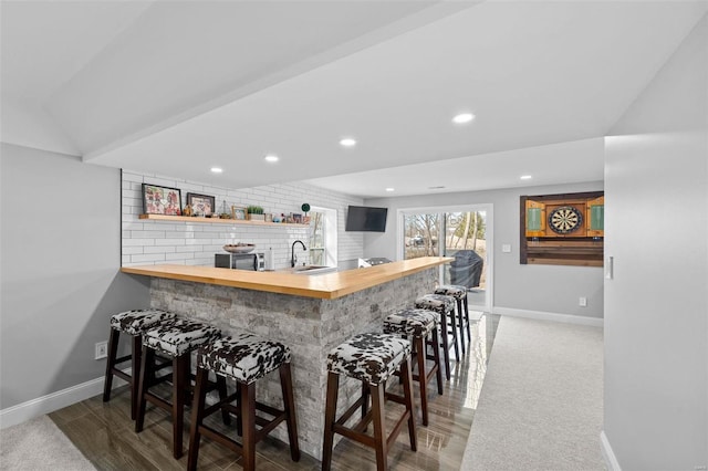 bar with indoor wet bar, a sink, and baseboards