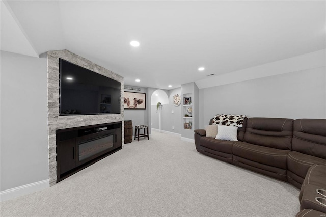 living room featuring arched walkways, a fireplace, carpet flooring, and baseboards