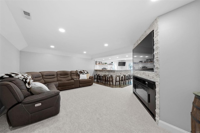 carpeted living area featuring a stone fireplace, bar area, visible vents, and recessed lighting