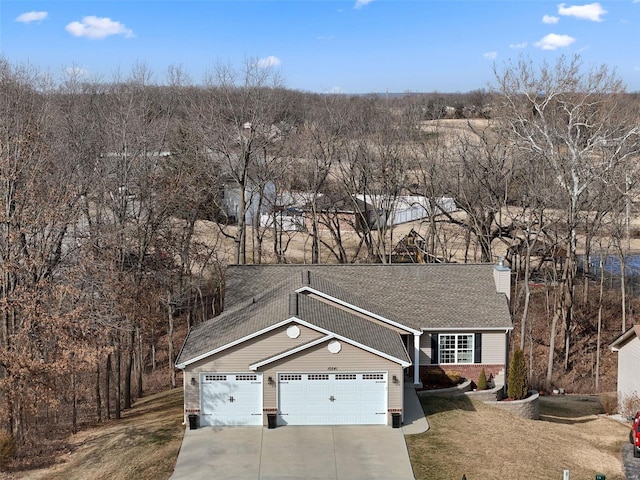 view of front of house with driveway, a garage, a chimney, and a front yard