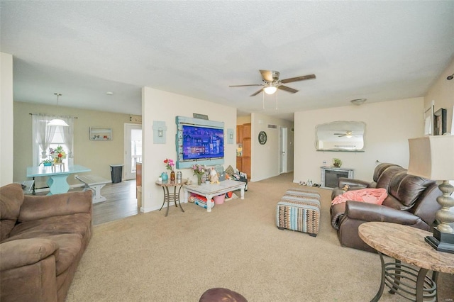 living area featuring ceiling fan, a textured ceiling, and light colored carpet
