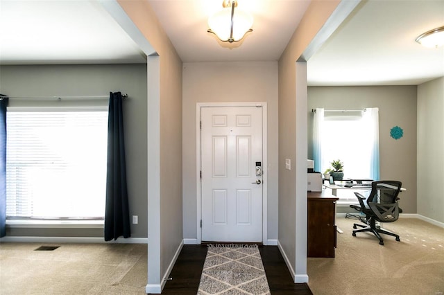 foyer with carpet, visible vents, and baseboards