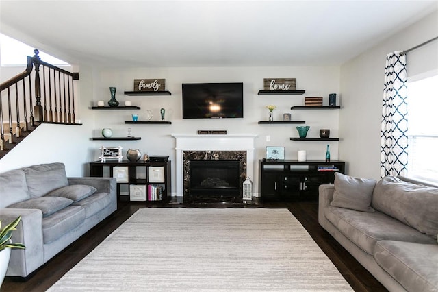 living area featuring dark wood-type flooring, a fireplace, and stairs