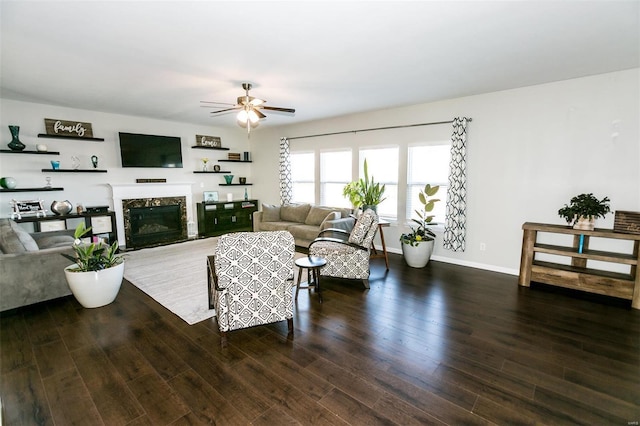 living area featuring ceiling fan, a fireplace, baseboards, and wood finished floors