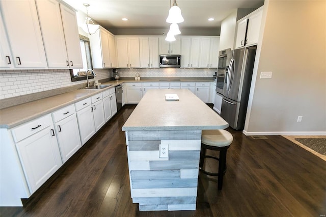 kitchen with a center island, dark wood-style flooring, stainless steel appliances, backsplash, and a sink