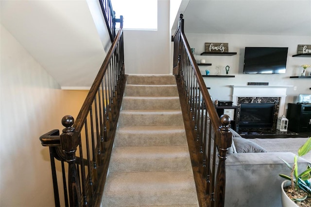 stairs featuring a high end fireplace and carpet