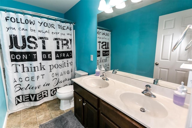 full bathroom featuring double vanity, tile patterned flooring, a sink, and toilet