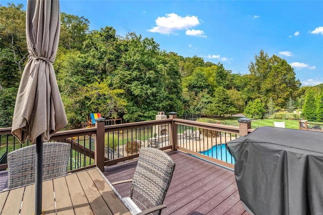 deck with grilling area, an outdoor pool, and fence