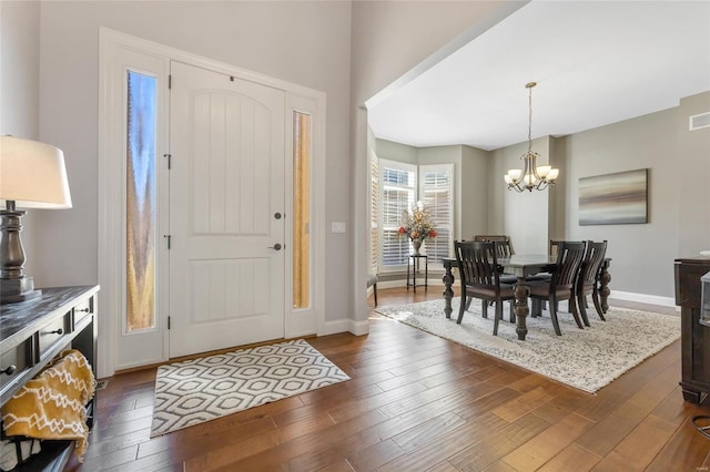 foyer entrance featuring visible vents, baseboards, an inviting chandelier, and dark wood finished floors