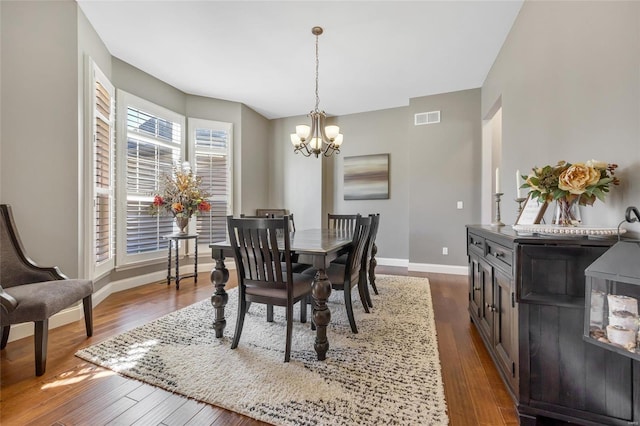 dining room with dark wood finished floors, visible vents, a notable chandelier, and baseboards