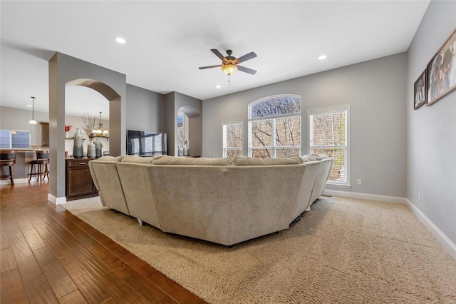 living area with wood finished floors, recessed lighting, arched walkways, and baseboards