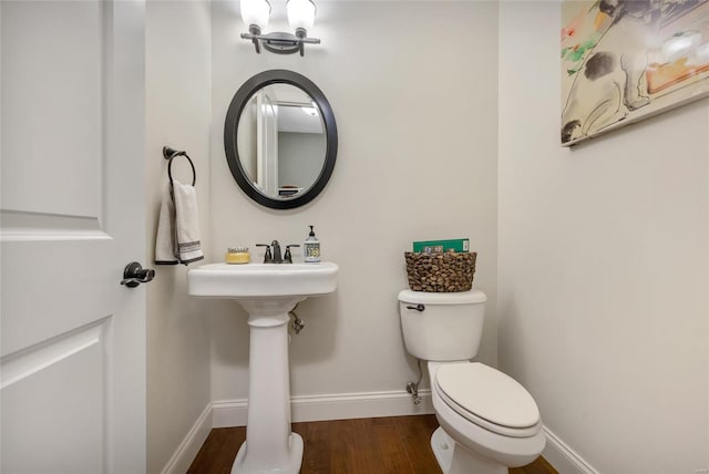 bathroom with toilet, wood finished floors, and baseboards