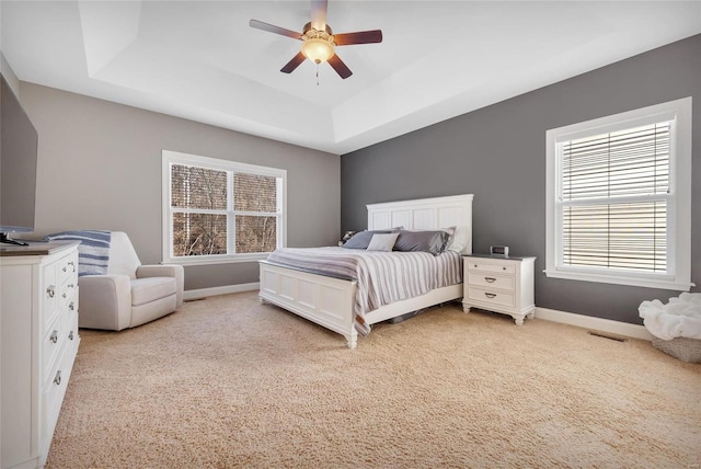 bedroom featuring a tray ceiling, baseboards, and multiple windows