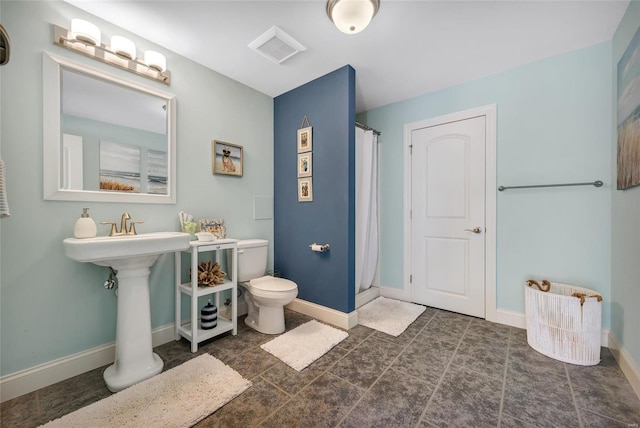 full bathroom featuring a shower with shower curtain, toilet, and baseboards