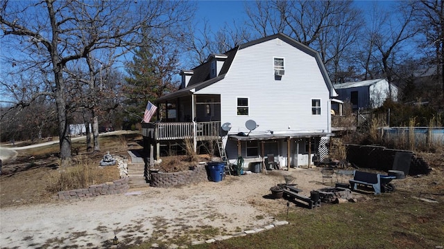 rear view of house featuring a sunroom, an outdoor fire pit, stairway, and a gambrel roof