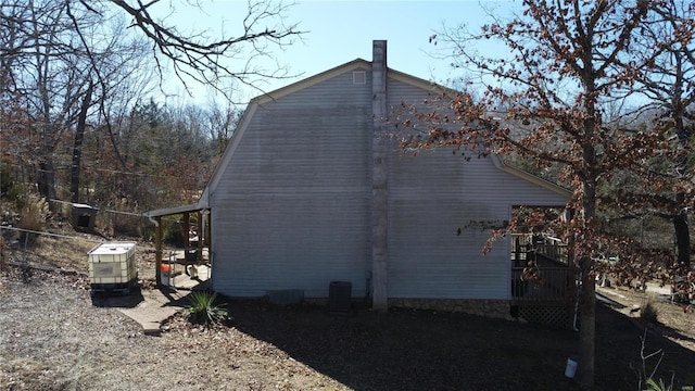 view of side of home featuring cooling unit and a gambrel roof