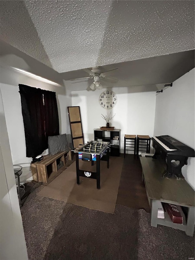 recreation room with carpet, ceiling fan, and a textured ceiling