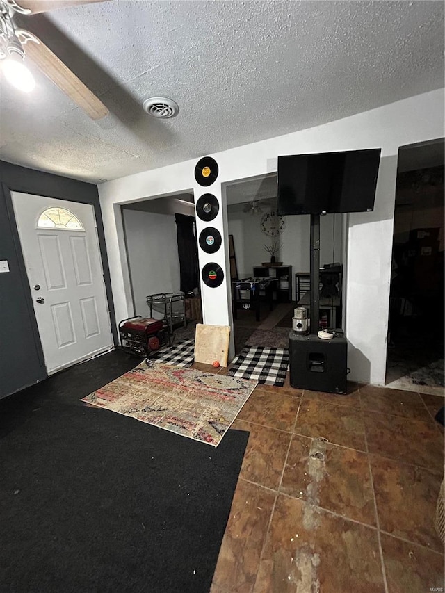 foyer featuring a textured ceiling, visible vents, and a ceiling fan