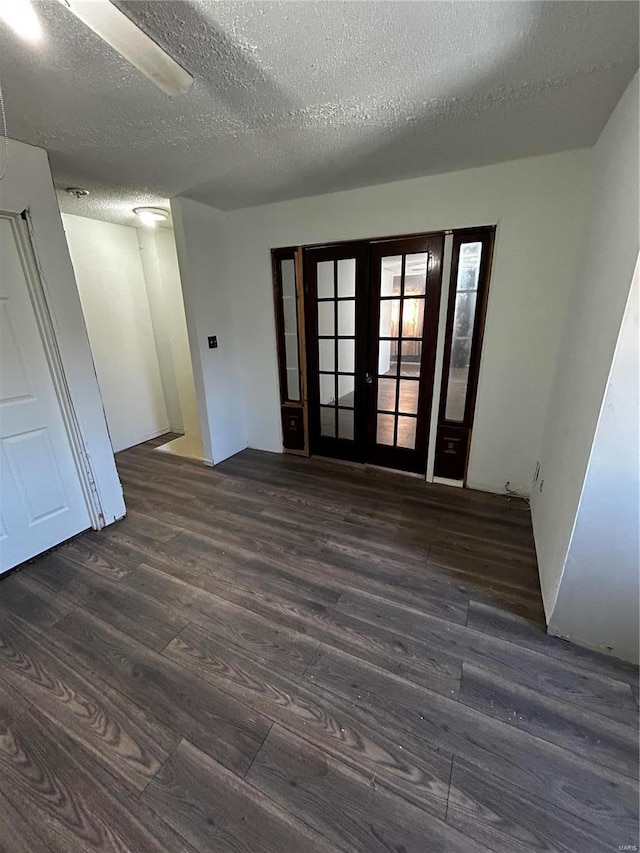 empty room featuring dark wood-style flooring, a textured ceiling, and french doors