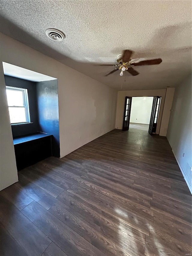 spare room with a textured ceiling, wood finished floors, visible vents, and a ceiling fan