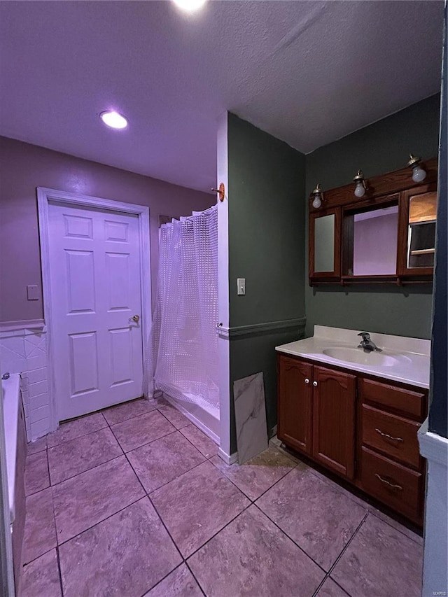 bathroom featuring a textured ceiling, a wainscoted wall, a shower with shower curtain, vanity, and tile patterned floors