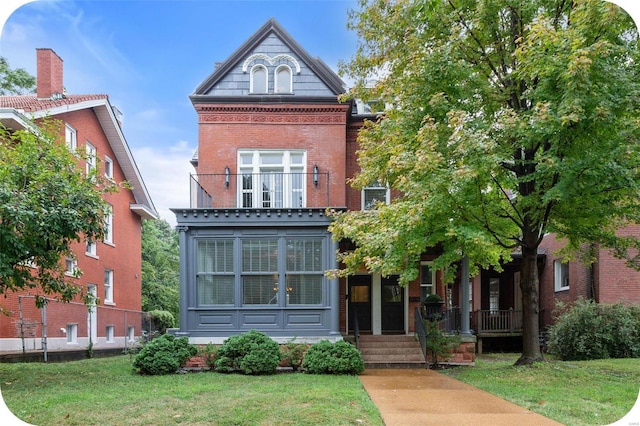 view of front facade featuring a porch, brick siding, a balcony, and a front lawn