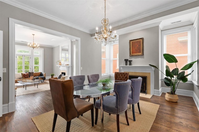 dining room featuring a chandelier, a fireplace with flush hearth, visible vents, dark wood-style floors, and crown molding