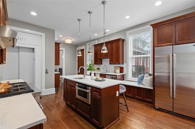 kitchen featuring stainless steel appliances, a kitchen island with sink, light countertops, and a sink