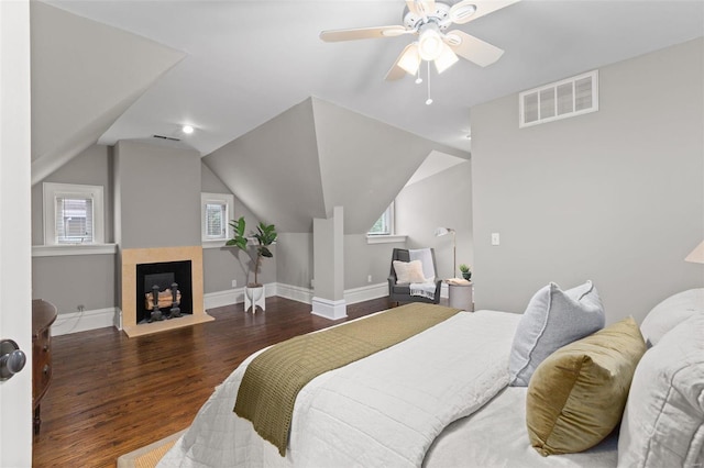 bedroom with wood finished floors, a ceiling fan, visible vents, vaulted ceiling, and baseboards