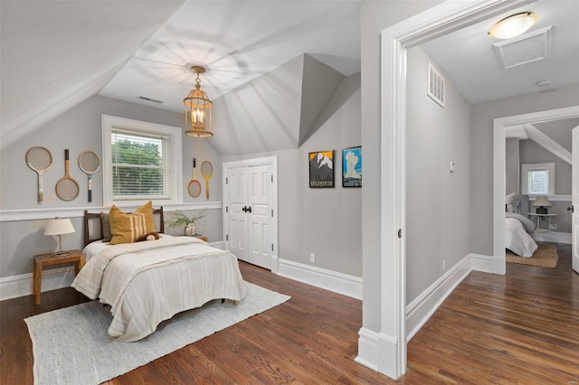 bedroom with vaulted ceiling, wood finished floors, visible vents, and baseboards