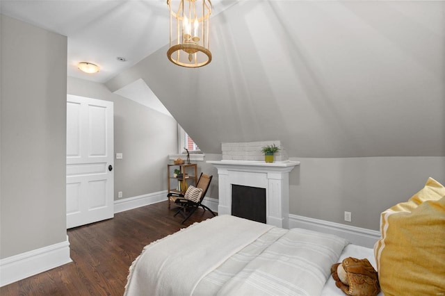 bedroom with a fireplace, baseboards, vaulted ceiling, and wood finished floors