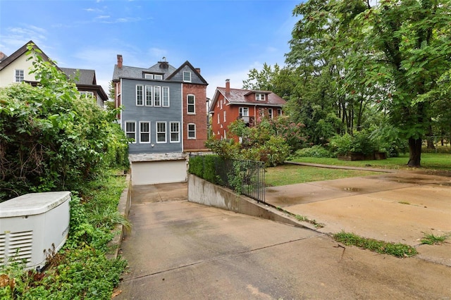 view of front of home featuring an attached garage, a chimney, a front lawn, and concrete driveway