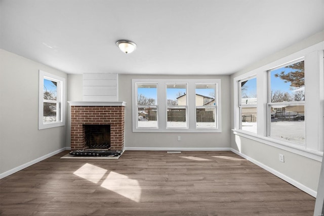 unfurnished living room featuring a fireplace, baseboards, and wood finished floors